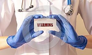 Vitamins word on white paper board in doctor hands. health concept