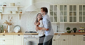 Vivacious spouses dancing together energetic dance in kitchen