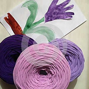 Vivid balls of eco t-shirt yarn zpaghetti for knitting are on background of children`s craft in the shape of hand