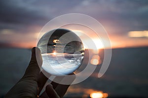 Vivid blue pink orange sunset seascape over ocean captured in glass ball