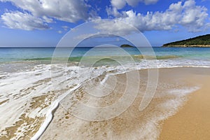 Vivid Caribbean scene of foaming white surf golden sand and very green blue sea and sky in Guadeloupe