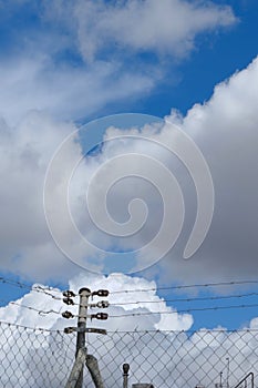 Vivid cloudscape with metallic net down. Conceptual for limits, border, loneliness, jail. Background for stories