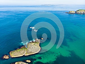 Vivid emerald-green water at Ballintoy harbour along the Causeway Coast in County Antrim. Rugged coast of Northern Ireland