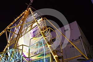 Vivid light trails dance as the swing ride glides through the air, adorned with a spectrum of colorful lights