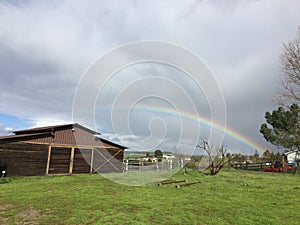 Vivid low Rainbow and barn with green grass