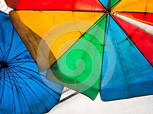 Vivid multi colored on the old and dirty beach umbrella