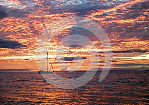 Vivid Orange Sunset Reflecting in Ocean Surface wtih Sailboat on