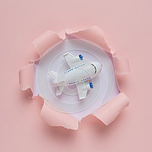 Vivid pink ripped paper with small airplane. Minimal travel concept