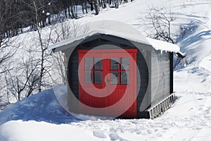 Vivid red hut on snow covered mountain in winter