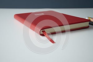 Vivid red notebook closed on white table with colored background