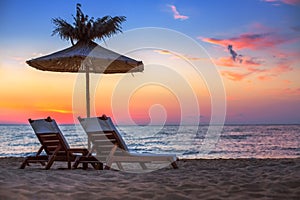 Vivid sunrise on a beautiful sandy beach with sunshade