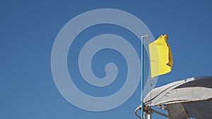 vivid yellow color flag banner flying on blue sky background with blowing wind for environment weather forecast with