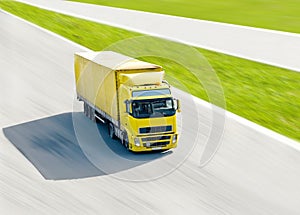 Vivid yellow truck in motion under bright sun