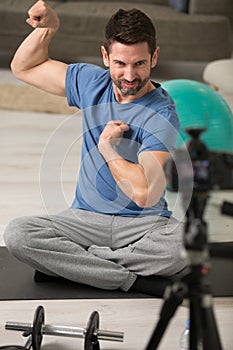 vlogger flexing muscles while filming exercise video photo