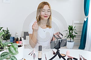 Vlogger testing decorative cosmetic and broadcast live video to social network at home. Blogging, videoblog, makeup