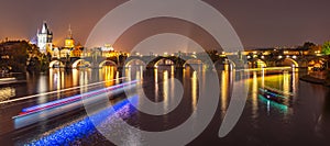 Vltava River with boat neon light lines and Charles Bridge with Old Town Bridge Tower by night, Prague, Czechia. UNESCO