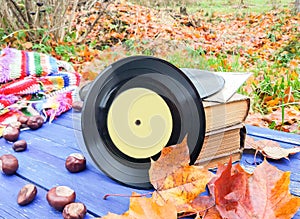 Vntage vinyl records on aged wooden background with bright handmade crocheted plaid, stackj of old books, chestnuts and fall
