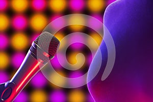 Vocal microphone next to woman figure with disco background lighting