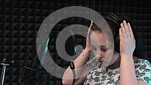 Vocal studio recording. Woman puts on headphones before singing in music studio