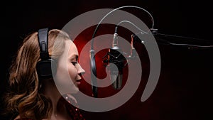 Vocalist, celebrity sings in a studio microphone with headphones on her head, live performance, vocals, vocal studio, track