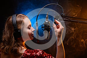 Vocalist singing in the studio. School and vocals. Against the backdrop of blue and orange smoke