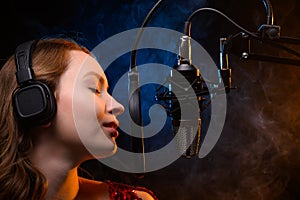 Vocalist singing in the studio. School and vocals. Against the backdrop of blue and orange smoke