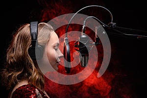 Vocalist singing in studio. School and vocals. Against the backdrop of red smoke photo