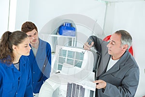 Vocational students learns air conditioning repair from experienced instructor