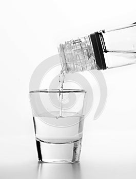 Vodka being poured to a glass. White background.