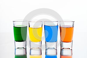 Vodka color shots filled with alcohol on glass bar table