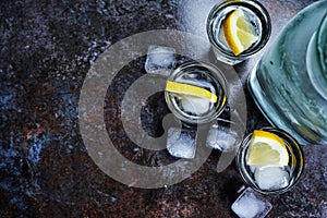 Vodka in glasses with lemon and ice. On the black stone table. Copyspace.