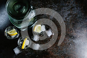 Vodka in glasses with lemon and ice. On the black stone table. Copyspace.