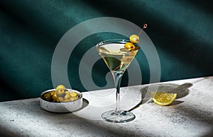 Vodka martini, classic alcoholic cocktail drink with vodka and vermouth, green olives garnish, dark background, bright hard light