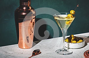 Vodka martini, classic alcoholic cocktail drink with vodka and vermouth, green olives garnish, dark background, bright hard light