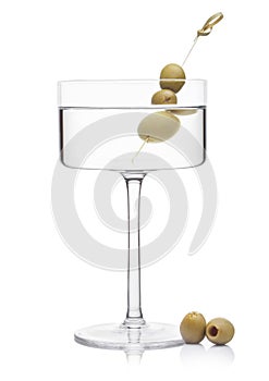 Vodka martini gin cocktail in modern glass with olives on bamboo stickwith fresh green olives on white background with reflection