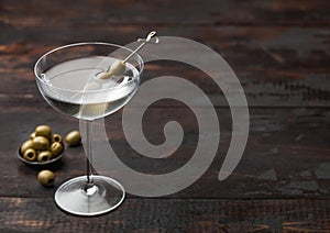 Vodka martini gin cocktail in modern glass with olives in metal bowl and bamboo sticks on wooden board