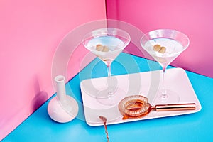 Vodka Martini with olive garnish. Long drink alcoholic cocktail on pink and blue background