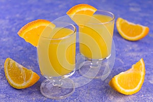 Vodka with orange juice in small glasses on a blue background.