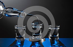 Vodka pouring from the bottle into a glass on a dark background