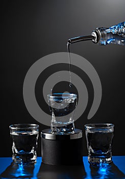 Vodka pouring from the bottle into a glass on a dark background