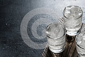 Vodka on the rocks on an old wooden table as detailed close-up shot