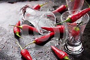 Vodka shot with chili peppers on rusty grunge table