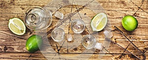Vodka in shot glasses on wooden background, iced strong drink in misted glass. Top view