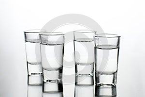 Vodka shots filled with alcohol on glass bar table