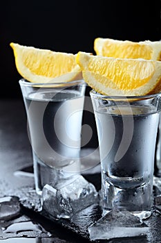 Vodka. Shots, glasses with vodka with lemon.Dark stone background.Copy space .Closeup.Selective focus