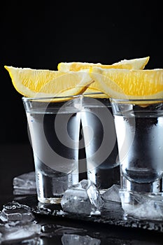 Vodka. Shots, glasses with vodka with lemon.Dark stone background.Copy space .Closeup.Selective focus