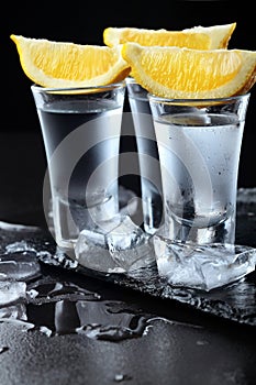 Vodka. Shots, glasses with vodka with lemon.Dark stone background.Copy space .Closeup.Selective focus