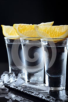 Vodka. Shots, glasses with vodka with lemon.Dark stone background.Copy space .Closeup.Selective focus