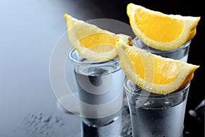 Vodka. Shots, glasses with vodka with lemon.Dark stone background.Copy space .Closeup.Selective focus