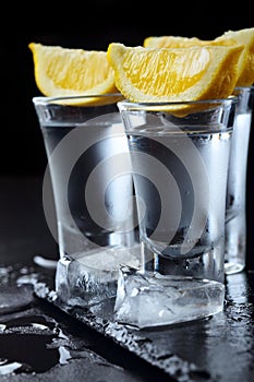 Vodka. Shots, glasses with vodka with lemon.Dark stone background.Copy space .Closeup.Selective focus